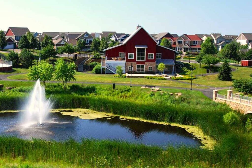 A red barn and a pond with a fountain, showcasing the peaceful environment for moving help in Woodbury MN.