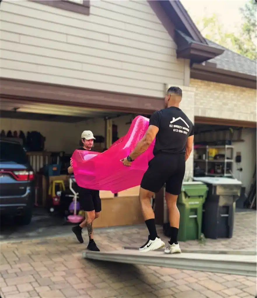 Two professional Minneapolis movers loading securely wrapped furniture into a moving truck.
