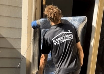 EZ Breezy Movers crew member providing expert Minneapolis residential moving services while moving furniture into a home in Uptown Minneapolis, MN.