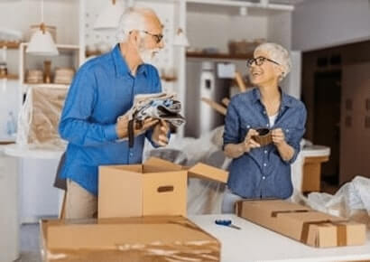 Smiling senior couple packing with EZ Breezy Movers, showcasing Minneapolis senior moving services in Northeast Minneapolis, MN.