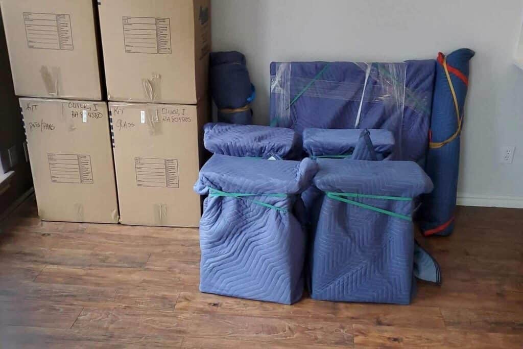 Apartment movers using moving pads securely wrapped around furniture for safe transport in a St. Paul apartment