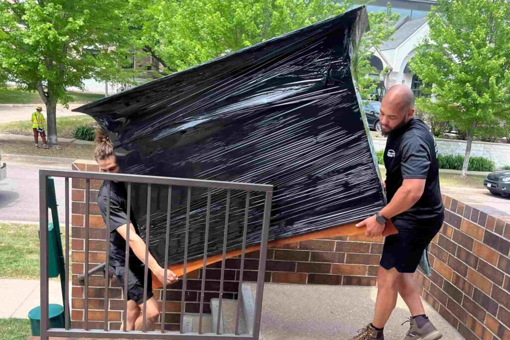 Woodbury Movers carrying a wrapped dresser down stairs in Woodbury MN